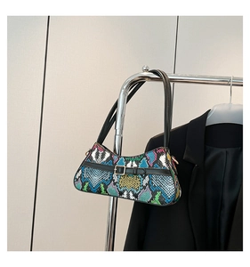 Detail of colorful snakeskin pattern on shoulder bag with black strap and gold buckle