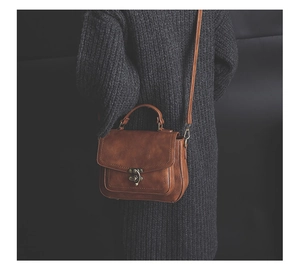 Brown PU leather crossbody bag with vintage bronze clasp worn over a gray sweater
