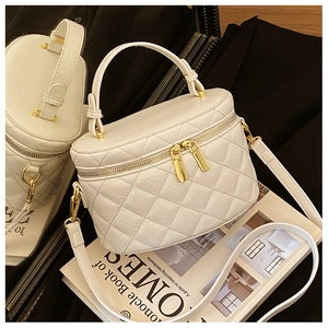 Close-up of cream quilted bucket bag featuring gold hardware and elegant double zippers