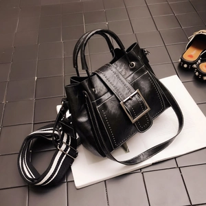 Detail of vintage matte leather handbag with metal buckle and striped shoulder strap