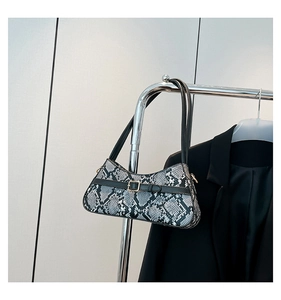 Detail of grey snakeskin baguette bag with black leather strap and gold square buckle