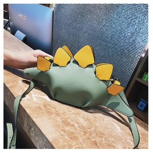 Detail of creative stegosaurus crossbody bag in green PU leather on marble surface