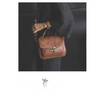Detail of vintage brown PU leather handbag featuring a metal turn-lock and stitching