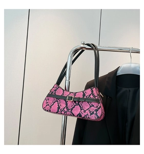 Detail of pink snakeskin pattern shoulder bag with black belt strap and gold buckle