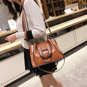 Detail of vintage brown leather tote bag with rivets and wide striped shoulder strap