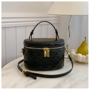 Detail of black quilted bucket bag with gold double zippers and texture on marble