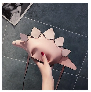 Detail view of pink stegosaurus crossbody bag made of matte PU leather with spikes