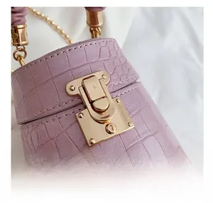 Close-up of golden metal lock and crocodile pattern leather on purple bucket bag