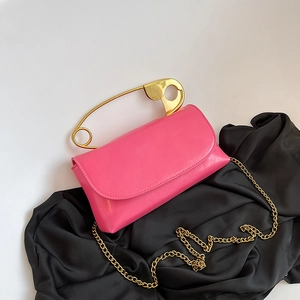 Pink PU leather shoulder bag with a unique oversized gold safety pin handle and chain strap