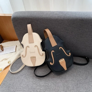 Violin-shaped fashion backpacks in black and cream PU leather on a modern sofa