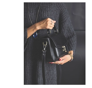 Detail of a vintage black PU leather handbag with a gold metal lock and shoulder strap