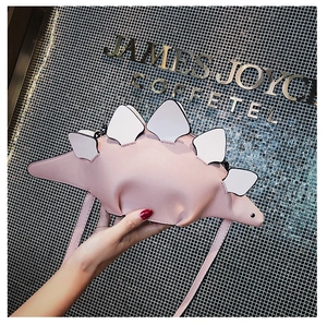 Close-up of a pink dinosaur-shaped mini crossbody bag with white dorsal fins