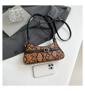Detailed view of crescent faux snakeskin bag next to a white smartphone for size reference