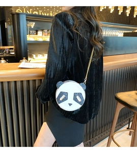 Detailed view of the panda-shaped sequin chain bag worn crossbody in a cafe setting