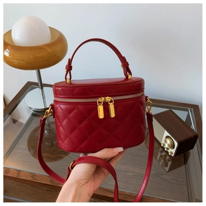 Detail of red quilted leather bucket bag with gold hardware and dual zipper closure