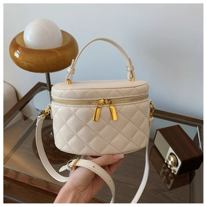 Detail of creamy white quilted mini bag with gold zippers and leather handle texture