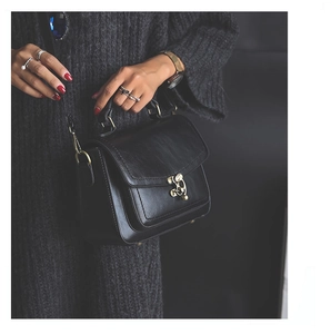 Detail of vintage black PU leather handbag with brass turn-lock and textured surface