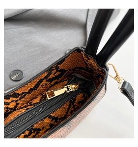 Macro shot of faux snake skin handbag interior with golden metal zipper and hardware