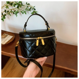 Detail of black quilted bucket bag featuring gold hardware and cylinder box shape