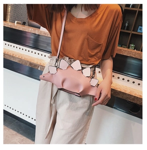 Detailed view of pink dinosaur crossbody bag with white plates on a model