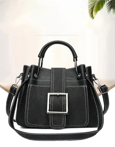 Detail of black pebbled leather handbag featuring white contrast stitching and silver buckle