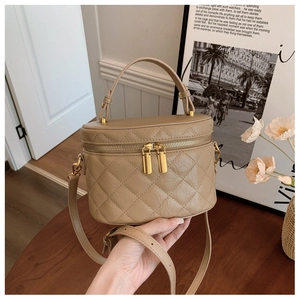 Detailed view of beige quilted bucket bag with gold zipper and adjustable strap
