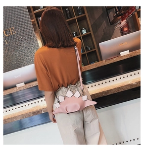 Detail showing pink dinosaur crossbody bag with white spikes and PU leather texture