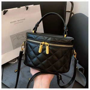 Close-up of black quilted leather bucket bag with gold zippers and top handle