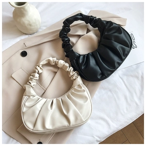 Detail shot of black and beige ruched dumpling bags on a blazer with stylish褶皱 handles
