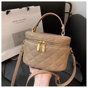 Detail view of beige quilted handbag with gold zippers and elegant top handle texture