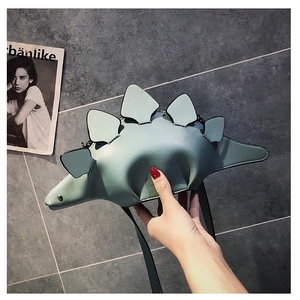 Detail of mint green dinosaur-shaped crossbody bag featuring soft stego plates