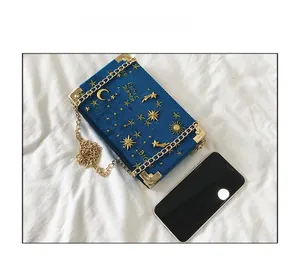 Comparaison de taille d'un sac boîte en velours bleu brodé et d'un smartphone