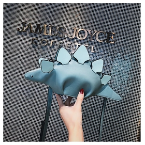 Detail shot of a grey-blue dinosaur crossbody bag with 3D fins and smooth PU texture