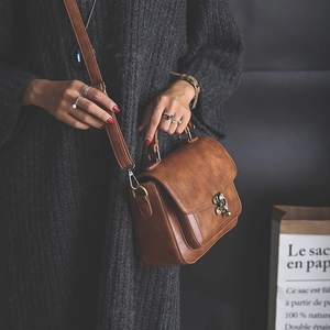 Vintage brown PU leather handbag with metal lock and top handle, styled on black knitwear