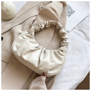 Detail of cream beige ruched dumpling bag with scrunchie handle on beige blazer