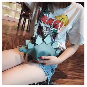 Detail shot of a small teal dinosaur crossbody bag with long strap and zipper closure