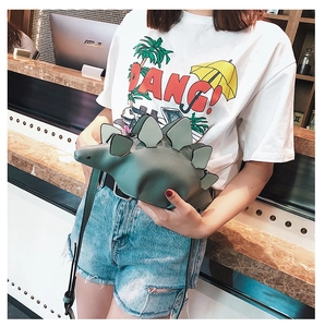 Detailed view of creative green dinosaur shaped crossbody bag worn by a person