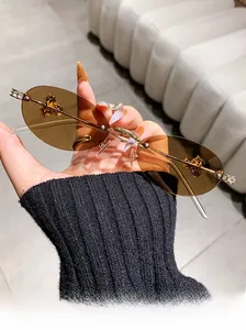 Detailed view of rimless oval sunglasses with brown lenses and diamond-encrusted temples
