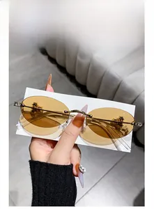 Detail of rimless oval sunglasses with gold cross accent and rhinestone hinge