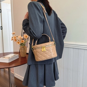 Quilted beige box bucket bag with top handle and gold zipper shown on a model