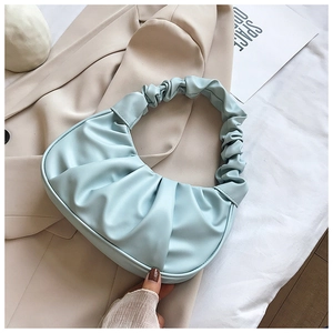 Detail of light blue pleated croissant bag on blazer, showing scrunched handle and crescent shape