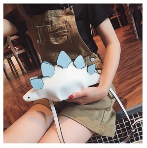 Detail shot of a white cartoon dinosaur crossbody bag with blue plates and PU strap