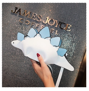 Detail view of white dinosaur crossbody bag with blue fins and stylish thin strap