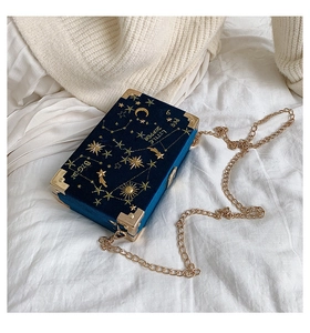 Détail du sac boîte en velours bleu marine avec broderie d'étoiles dorées et chaîne