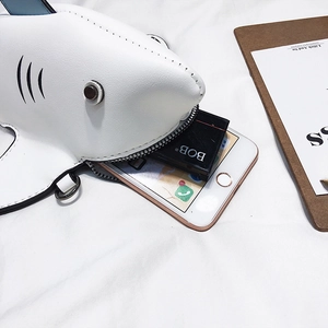 Quirky white shark-shaped crossbody bag with fins showing storage for phone and makeup