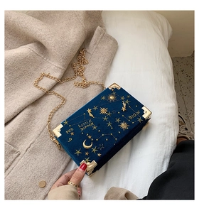 Détail du sac boîte en velours bleu foncé avec broderies célestes dorées et chaîne