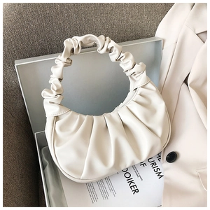 Detailed view of cream ruched dumpling bag with scrunchie handle in stylish setting