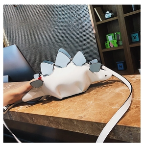 Detailed view of creative white dinosaur shaped crossbody bag with blue spiky plates