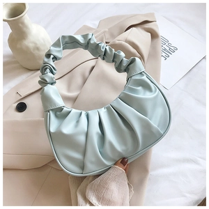 Detailed view of ruched light blue crescent bag on beige suit for fashion aesthetic