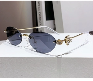 Close-up of rimless oval sunglasses with gold frame and large crystal rhinestones on temples